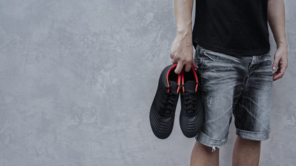 Man holding football boots in his hand.