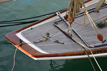 Stern of vintage wooden yacht with teak deck and classic wooden blocks and natural fiber ropes.