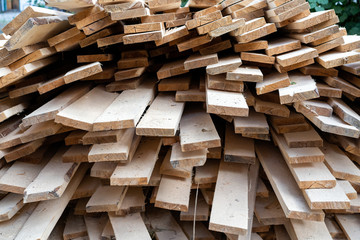 a pile of wooden planks lying on the street. wooden building material. A lot of wooden planks lying on the ground. Wooden sticks are lying on the ground. lumber lying on the street. Pine board cut