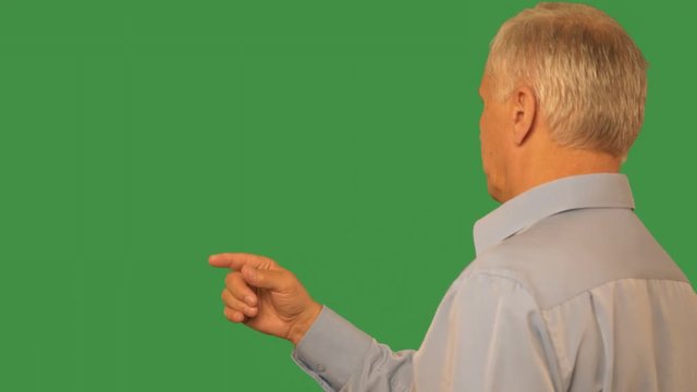 Senior man swiping by finger virtual screen on transparent green background. Mature man sliding on monitor while browsing on green background. Alpha channel, keyed green screen. Unrecognized person