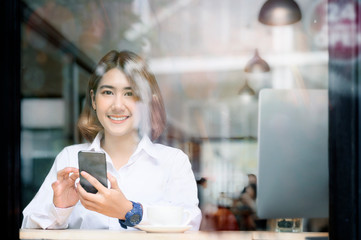 Fototapeta na wymiar Portrait of pretty woman using smartphone in coffee shop.