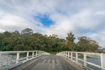 Fototapeta na wymiar Wooden arch bridge over river. Rural countryside infrastructure