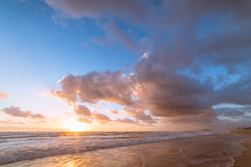 Fototapeta na wymiar Beach sunrise with beautiful clouds and mild waves
