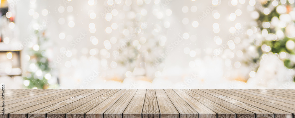 Leinwandbilder Empty woooden table top with abstract warm living room decor with christmas tree string light blur background with snow,Holiday backdrop,Mock up banner for display of advertise product.
