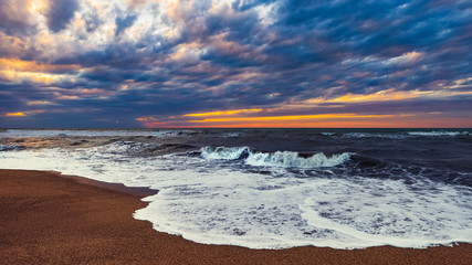 Beach with waves at colorful sunset
