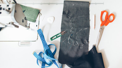 Jeans manufacturing. Flat lay of fabric pattern, scissors, tapeline on seamstress workplace.