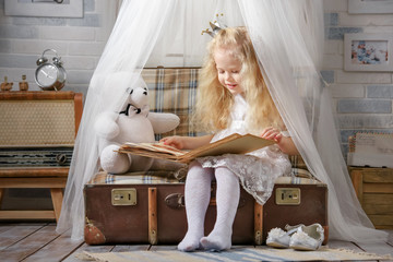 Little girl dressed as a princess plays in the room in the attic.
