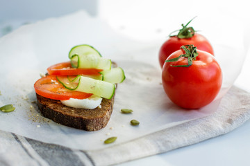 Fototapeta na wymiar Sandwich with tomato, cucumber and seeds on whole grain bread. The concept of healthy eating.