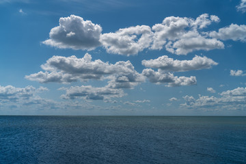 white clouds float in the sky above the sea