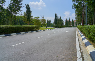 The asphalt road in the park with green grass background .