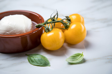 Gelbe Tomaten mit Mozzarella und Basilikum auf Marmor Hintergrund 