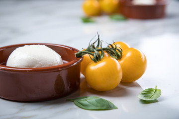 Gelbe Tomaten mit Mozzarella und Basilikum auf Marmor Hintergrund 