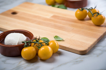Gelbe Tomaten mit Mozzarella und Basilikum auf Holz Brett 