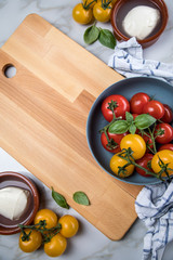 Rote und gelbe Tomaten mit Mozzarella und Basilikum auf Holz Brett mit Geschirrtuch