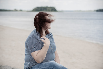 Fototapeta na wymiar Sad Simple plump middle aged woman thinking about something, crisis of middle age and problems among overweight people 