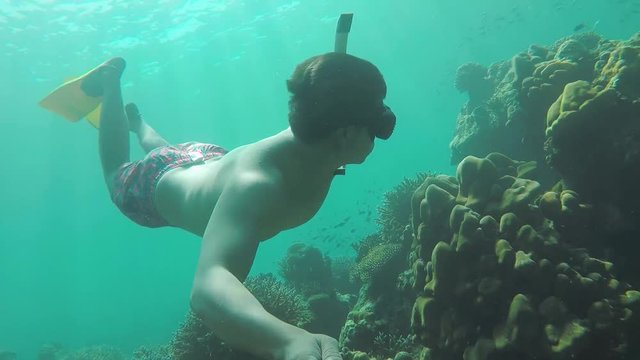 A man snorkeling and swimming under water among the coral and fish Selfie shots. Surin Islands,Thailand