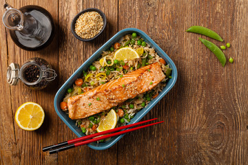 Asian dish. Fried salmon with rice and vegetables. Sprinkled with sesame seeds.