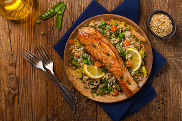 Asian dish. Fried salmon with rice and vegetables. Sprinkled with sesame seeds.