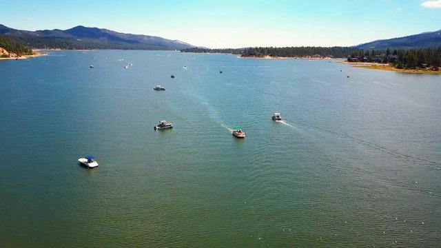 Aerial drone pushing forward shot, of Big Bear Lake over boats showing the wide open lake, California
