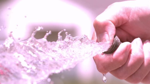 Garden hose water with thumb spraying out slow motion