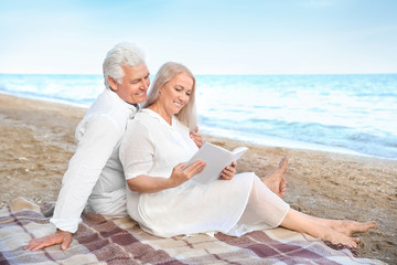 Fototapeta premium Happy mature couple reading book at sea resort