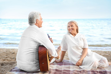 Mature man playing guitar for his wife at sea resort