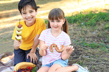 Happy little children having picnic on summer day