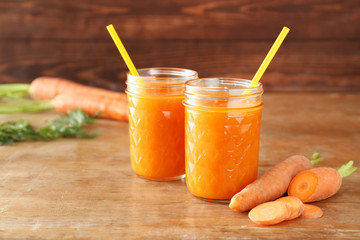 Jars of tasty carrot juice on wooden table