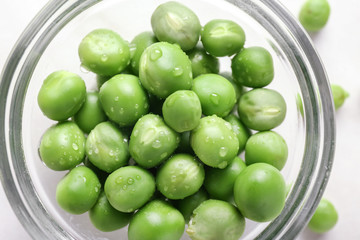 Bowl with tasty fresh peas on light background, closeup