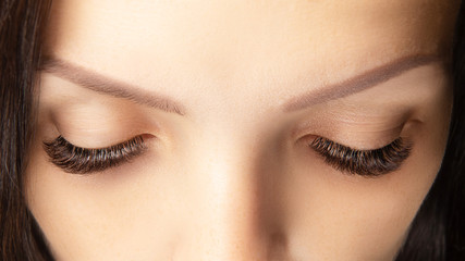 Eyes with beautiful long lashes closeup. Brown color eye lash extension, 3D or 4D volume. Eyelash...