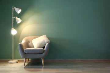 Interior of modern room with armchair and lamp in evening - obrazy, fototapety, plakaty