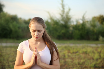 Naklejka na ściany i meble Young woman praying to God outdoors