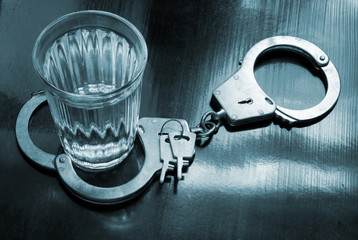 Alcoholism concept, glass with vodka and handcuffs with keys