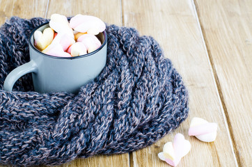 Cup of hot cocoa with marshmallows, woolen warm scarf, cozy winter evening