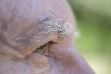Closeup eye of caucasian old man. Portrait of old man outdoors. Caucasian male face background, close up eyes, macro