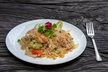 Fried rice with shrimps and vegetables in a white dish on an old wooden table, close up . Thai food , Thai cuisine