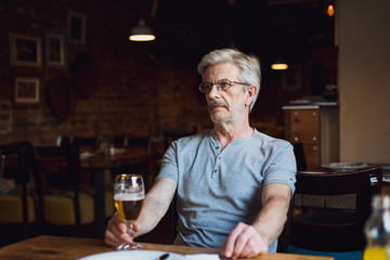 Senior man with a beer in the bar