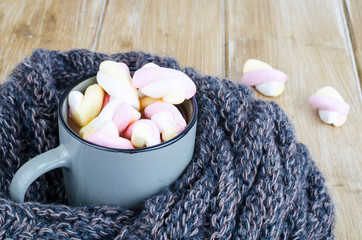 Cup of hot cocoa with marshmallows, woolen warm scarf, cozy winter evening
