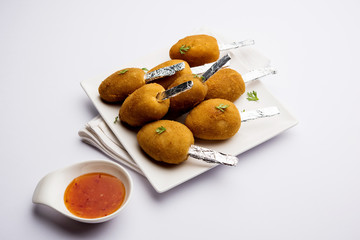 Crispy Veg lollipop recipe made using boiled potato with spices covered with corn flour and bread crumbs coating and then deep fried, served with toothpick or ice cream stock inserted in it with sauce