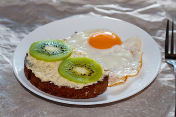 Delicious and healthy breakfast. Scrambled eggs and kiwi sandwich on a white plate, close-up, top view and side view