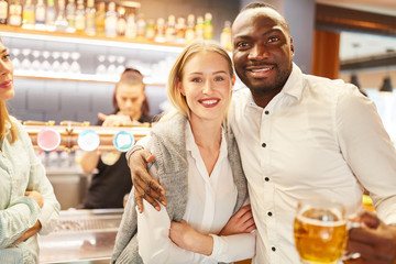 Multicultural couple having beer in pub