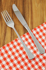 Knife and fork with tablecloth on wooden table background