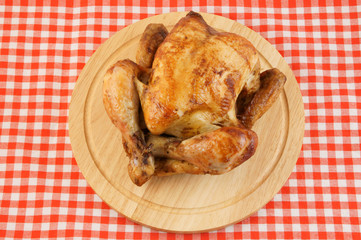 Roasted chicken on cutting board on tablecloth