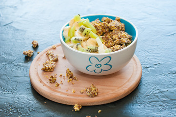 Granola, kiwi, banana and yogurt in a bowl on a wooden stand, gray background, view from the top. Fitness diet for weight loss