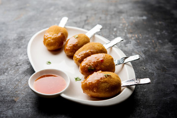 Crispy Veg lollipop recipe made using boiled potato with spices covered with corn flour and bread crumbs coating and then deep fried, served with toothpick or ice cream stock inserted in it with sauce
