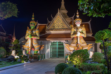 Wat Arun Temple of Dawn Buddhist temple with guardians protecting gates. Bangkok, Thailand.