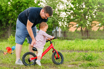 Young father spend time with Cute little one years old toddler girl child and balance bike, father's day