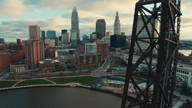 Aerial drone dolly shot from behind rusty old lift bridge in the flats to reveal downtown Cleveland Ohio