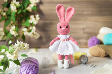 Knitted toy rabbit Handmade on wooden table. Crochet stuffed animals.
