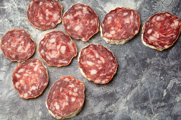 Traditional Spanish Fuet thin dried sausage with slices on grey stone background